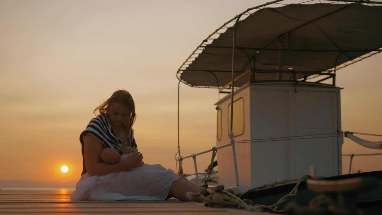 Mother sitting by a boat with her baby