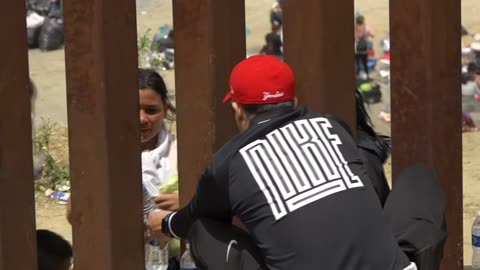 Volunteers hand water to migrants through US-Mexico border fence