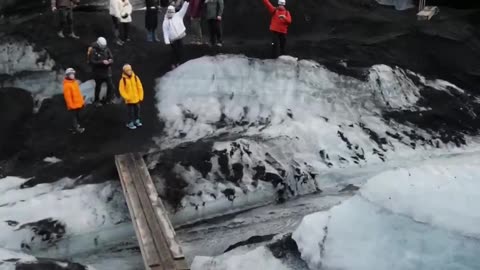 Drone Explores a Glacier-Altered Landscape as a Group of People Ventures