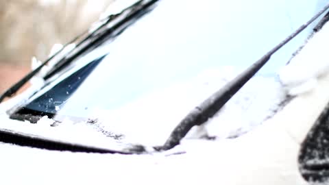 Use the wiper to remove the thick snow from the car glass.