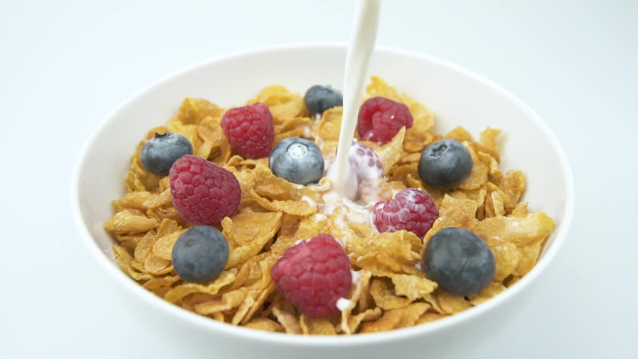 Pouring fresh milk over a bowl of cereal