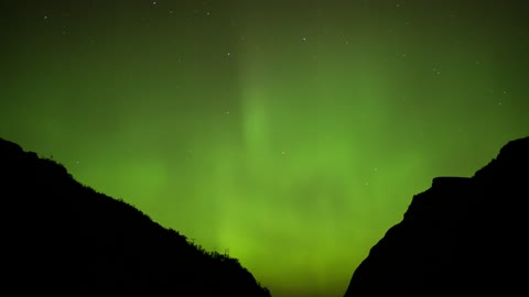 Northern Lights behind two mountains