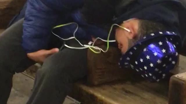 Man with blue hat lights asleep on subway bench