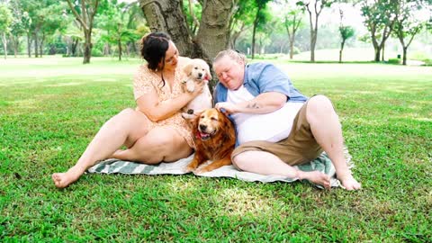 Couple Sitting on Grass with Their Dogs