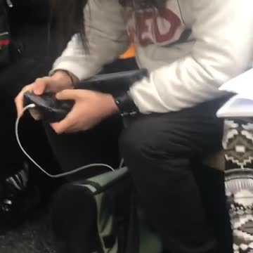 Guy uses controller to play portable game on subway train