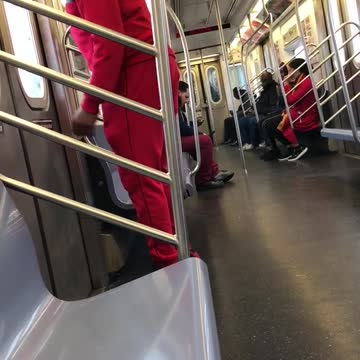 Man in red sweats dances by subway doors