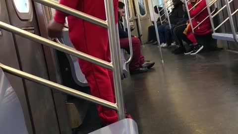 Man in red sweats dances by subway doors