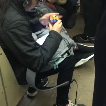 Woman solves a rubik's cube very fast on subway train and times herself