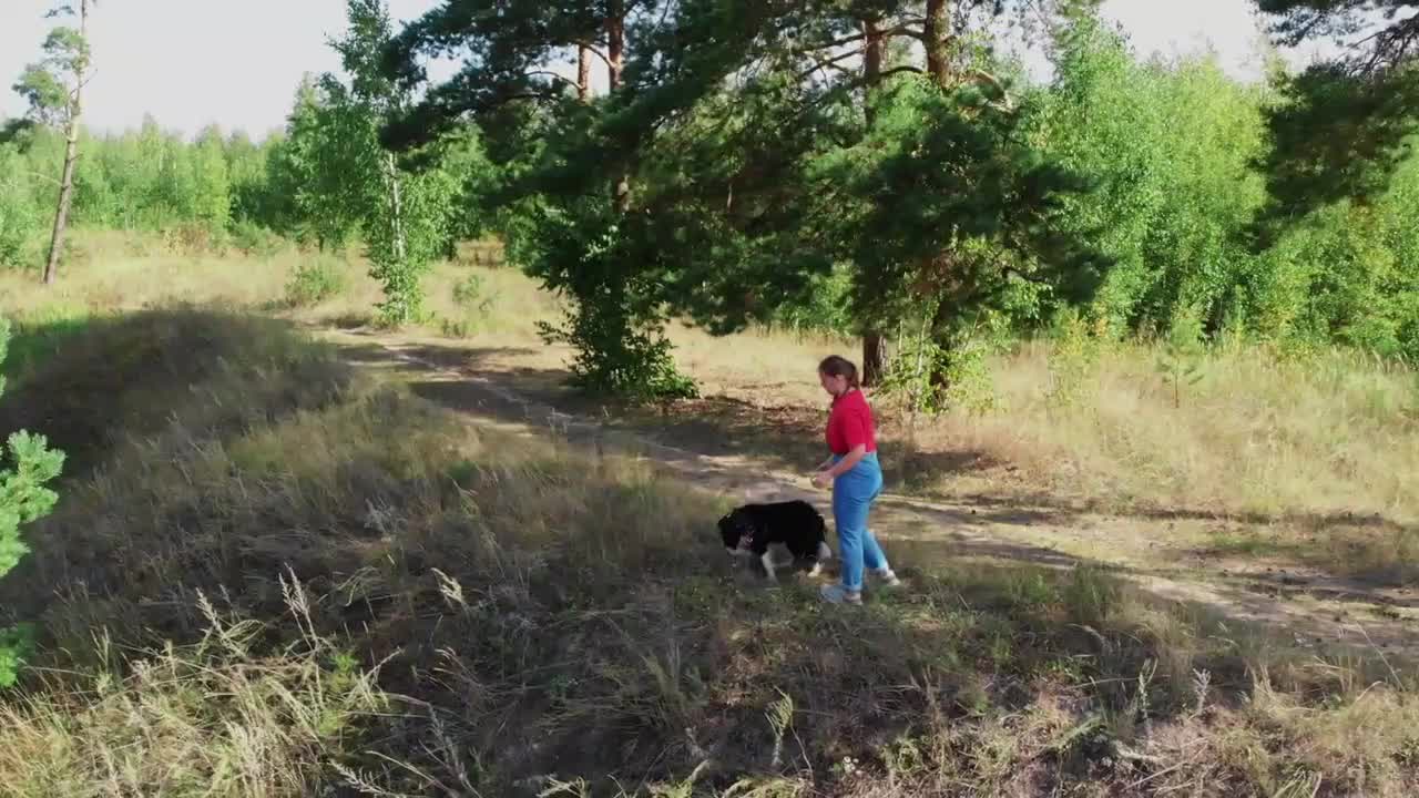 Young plump woman and her cute dog playing outdoors together