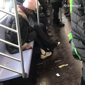 Man in pink white beanie smokes on a subway train
