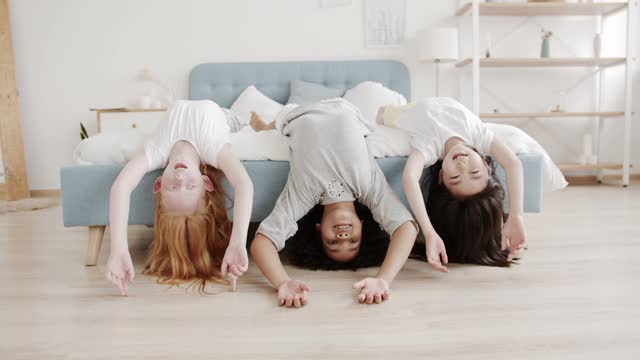 Young Girls Lying on Bed with Their Hairs Touching Floor