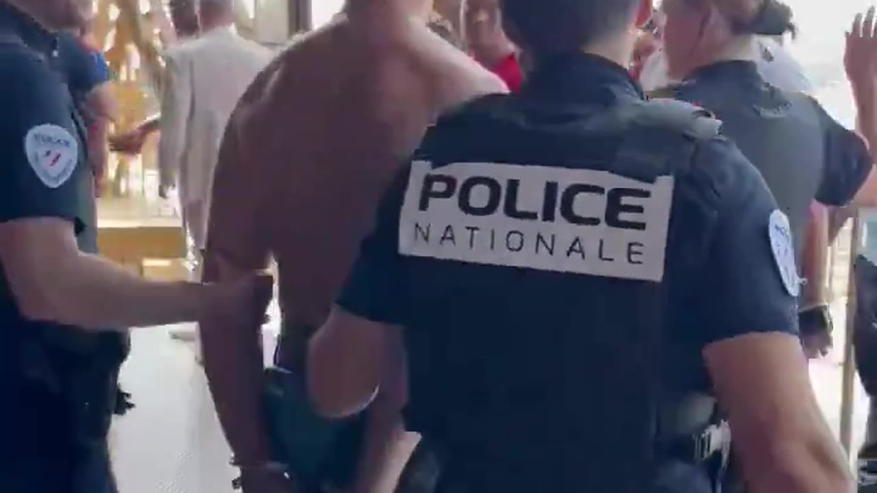 British man who scaled the Eiffel Tower topless earlier today smiled as he was