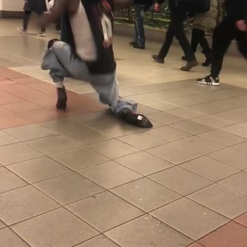 Man in heals and black shirt dancing subway station