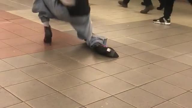 Man in heals and black shirt dancing subway station