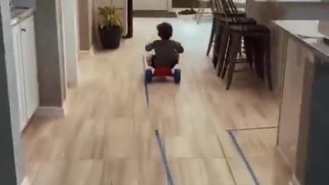 A child rides a toy bike at home