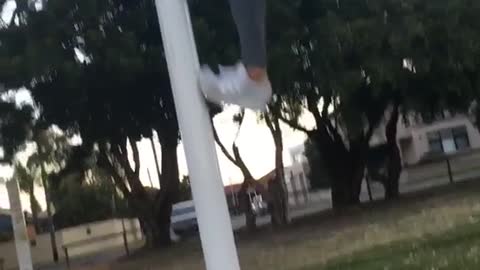 Girl in grey leggings and white shirt tries to climb light pole fail