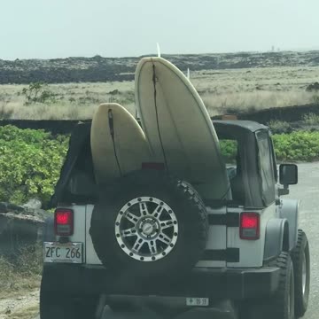 Cars driving with surfboards onto beach