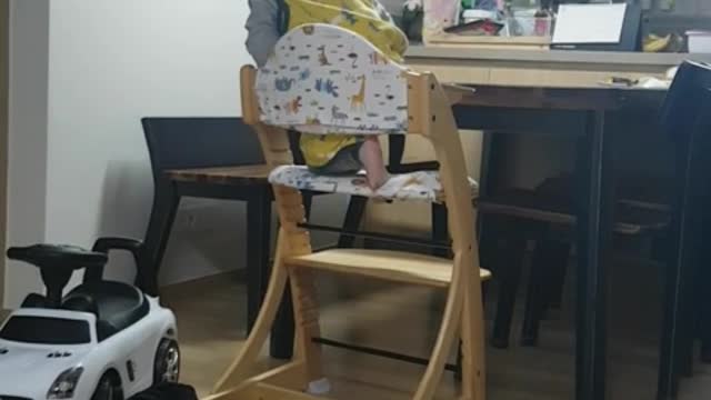 This is a video of a baby climbing on a chair by himself.