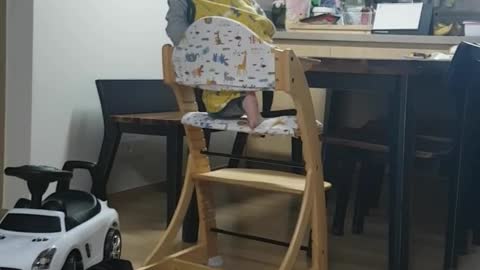 This is a video of a baby climbing on a chair by himself.