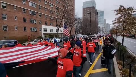 100s of NYC workers carry an American and Canadian flag while fighting mandates