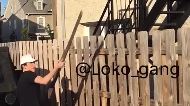 Guy in white hat tosses wood across fense