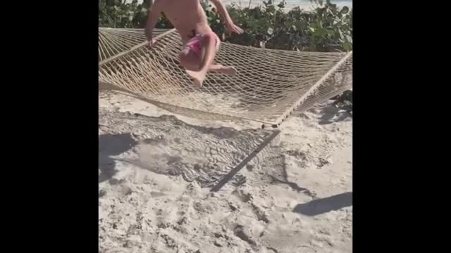Guy tries to be cool but falls off hammock into sand