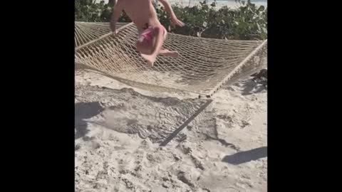 Guy tries to be cool but falls off hammock into sand