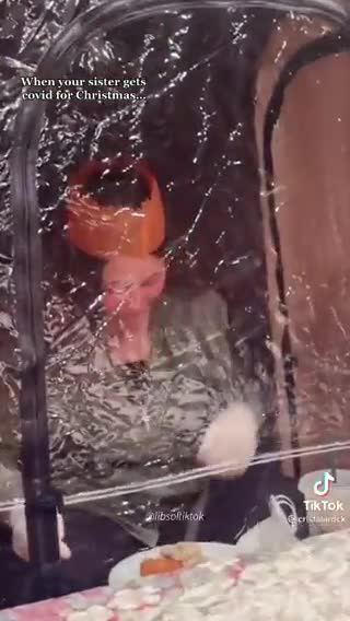 The Madness of others- girl sits in a see-through tent at the table with her family for lunch