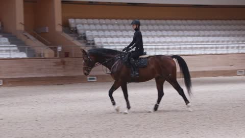 A horsewoman slowly riding a horse on a horse racing track