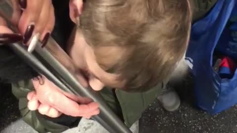 Little boy licking pole on subway