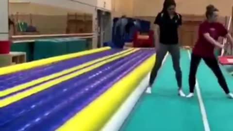 Black shirt girl tumbles down blue yellow runway falls on back