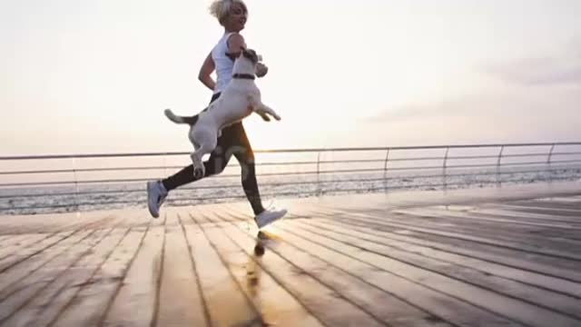 Wao 🥰Young woman running with cute dog Jack Russel near the sea,