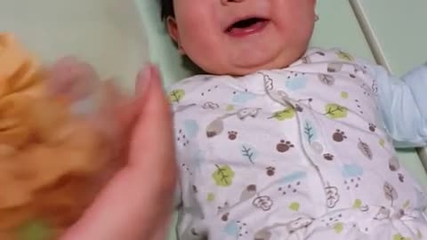 This is a video of a baby laughing so much at the sound of shaking cookies.