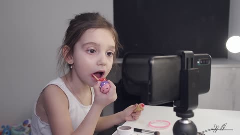 Little girl putting on lipstick