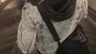 Guy rides down escalator with rat crawling on shoulders and neck