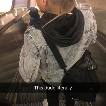 Guy rides down escalator with rat crawling on shoulders and neck