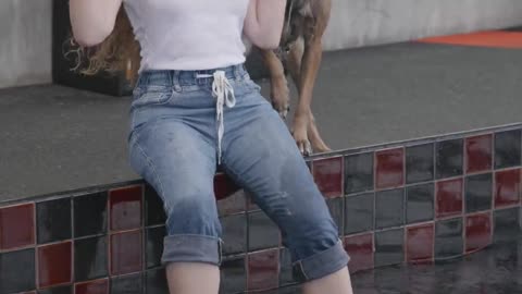 funny girl playing with dog at poolside