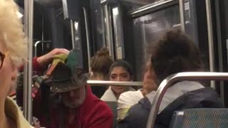 Man with red shirt brown hat two birds on hat