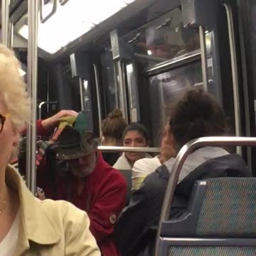 Man with red shirt brown hat two birds on hat