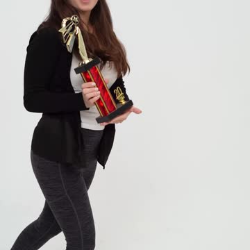 Young Woman Dancing while Holding Trophy