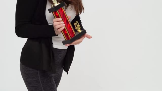 Young Woman Dancing while Holding Trophy