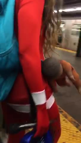 Woman in red with baby strapped to side