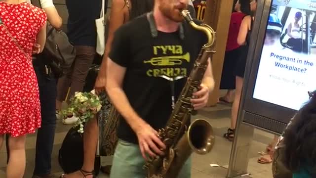 Guy black shirt shorts playing sorry not sorry in subway on saxophone