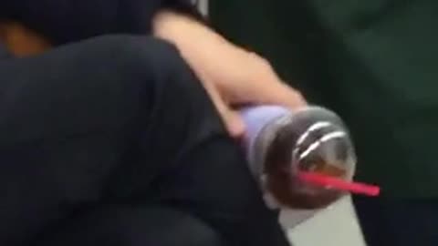 Ice coffee barely hanging on man asleep on subway