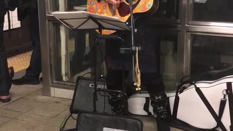 Man with basket on head plays weird guitar