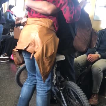 Man and woman hugging next to bike on subway train
