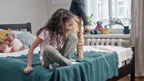 Kids Playing Catch The Bait With Their Cat In The Bedroom.