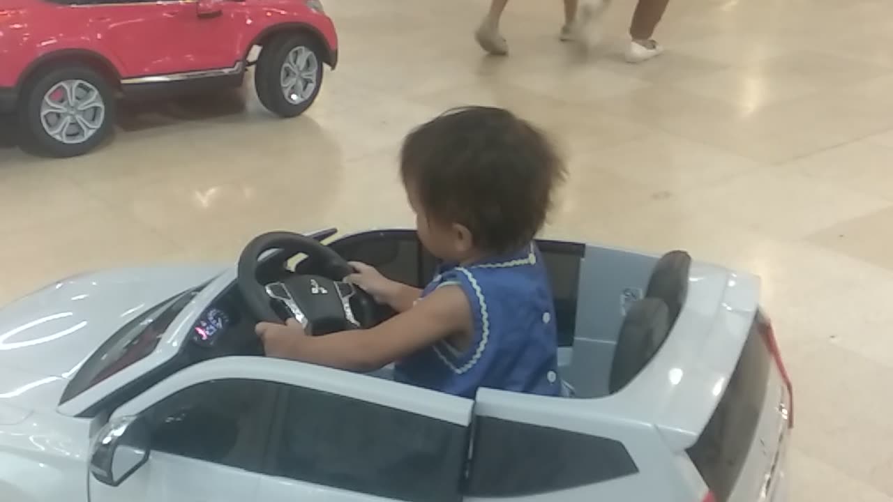 Little Akai rides in a toy car