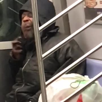 Guy in black hoodie brushing beard on subway