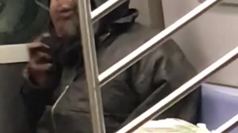 Guy in black hoodie brushing beard on subway